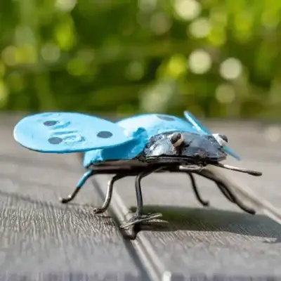 Sculpture coccinelle bleu en métal dans un jardin 2
