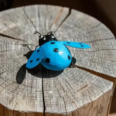 Sculpture coccinelle bleu en métal dans un jardin 2